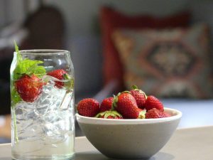 freshly picked strawberries in bowl and on ice in a drink